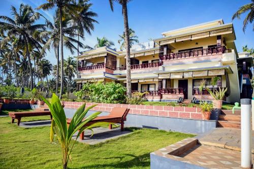 een groot huis met palmbomen ervoor bij Maadathil Beach Resort in Varkala