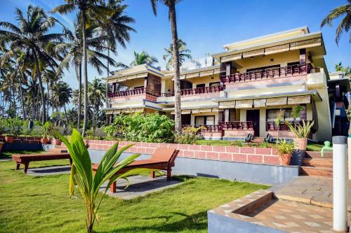 una casa grande con palmeras delante en Maadathil Beach Resort en Varkala