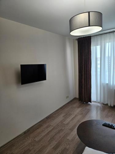 sala de estar con mesa y TV en la pared en 1 kambario butas self check in, en Šiauliai