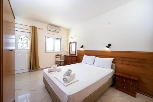 a bedroom with a bed with white sheets and a mirror at Mammis Beach Hotel in Kardamaina