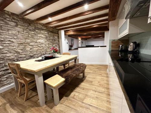 a dining room with a table and a stone wall at Hay On Wye Welsh Townhouse in Hay centre in Hay-on-Wye