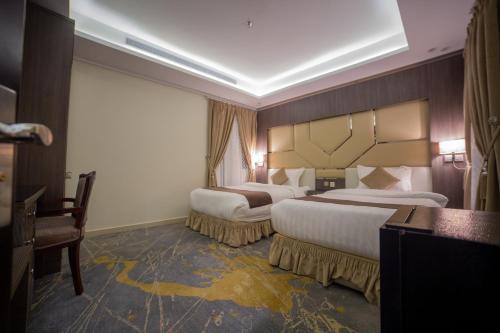 a hotel room with two beds and a desk at Guest House Hotel Apartments in Yanbu