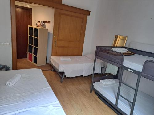 a room with two bunk beds and a wooden door at Alojamiento Compartido En Rambla De Cataluña in Barcelona
