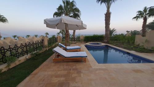 einen Pool mit 2 Liegestühlen und einem Sonnenschirm in der Unterkunft fourseasons resort - privte villa at fourseasons sharm elsheikh in Sharm El Sheikh
