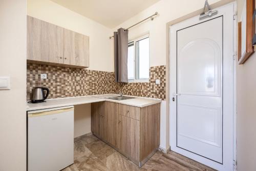 a small kitchen with a sink and a door at Mammis Beach Hotel in Kardamaina
