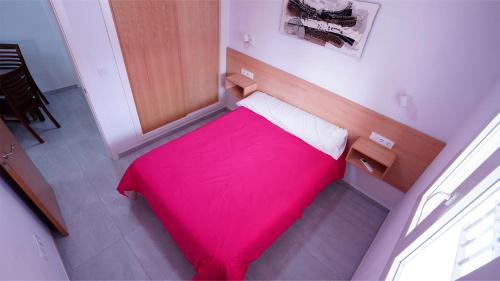 1 cama pequeña con manta roja en una habitación en APARTAMENTO TURÍSTICO CASA MIGUEL, en Matalascañas