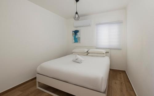 a small bedroom with a white bed and a window at Central and beautiful - MORE apartments in Beer Sheva