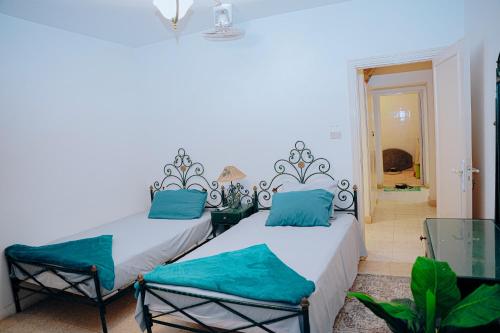 two beds in a white room with blue pillows at 4 bedrooms villa with private pool in Tunis village faiuym in Qaryat at Ta‘mīr as Siyāḩīyah