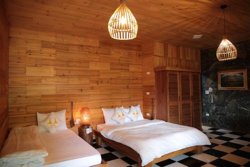 two beds in a room with wooden walls at Ha Giang Historic House & tour in Ha Giang