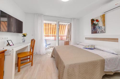 ein Schlafzimmer mit einem Bett und einem Tisch sowie eine Küche in der Unterkunft Cosy Studio Playa del Cura in Torrevieja