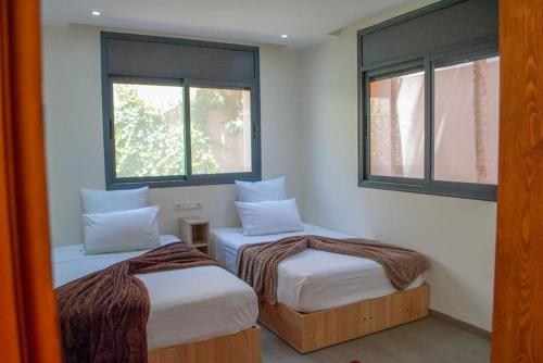 Aït Imouni的住宿－Villa et 3 bungalows Vert，带2扇窗户的客房内的2张床
