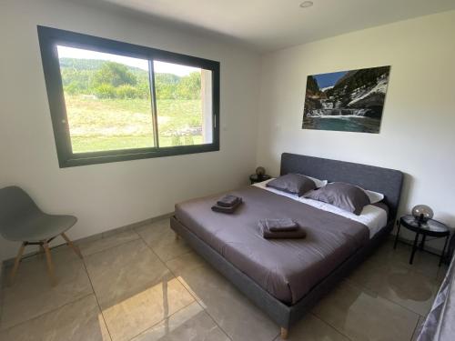 Schlafzimmer mit einem Bett, einem Fenster und einem Stuhl in der Unterkunft Magnifique Villa Sabot de Venus in Le Lautaret