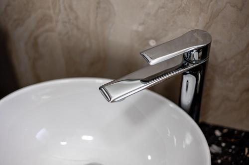 a white toilet with a silver faucet in a bathroom at ForS Resort & Spa in Belgrade