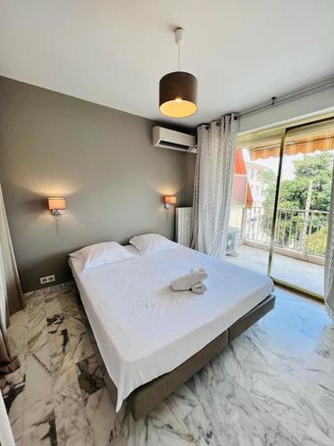 une chambre avec un grand lit avec une grande fenêtre dans l'établissement Le Pinède - Apt 4 Prs- Clim - 500m plages, à Antibes