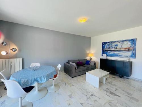 a living room with a table and a couch at Le Pinède - Apt 4 Prs- Parking - Clim - 500m plages in Antibes