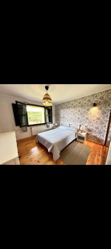 1 dormitorio con cama blanca y pared de piedra en El Acebu, en Colombres