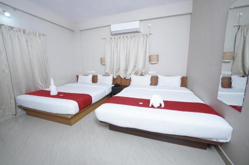 a bedroom with two beds with red and white sheets at DREAMS AIRPORT RESIDENCY in Nedumbassery