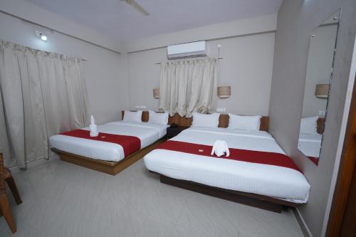 two beds in a room with white and red sheets at DREAMS AIRPORT RESIDENCY in Nedumbassery