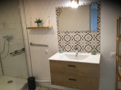 een badkamer met een wastafel, een spiegel en een douche bij HoLiDaYs in Arques
