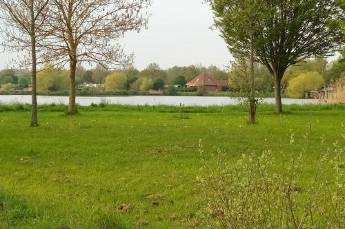 een grasveld met bomen en een waterlichaam bij HoLiDaYs in Arques