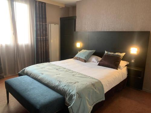 1 dormitorio con 1 cama grande y 1 reposapiés azul en Hôtel Noz Vad en Carhaix-Plouguer