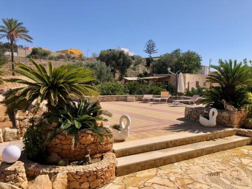 un giardino con statue di cigni e palme di Villa Oasi Dei Sogni a Lampedusa