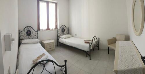 a white room with two beds and a mirror at PM 15 Via Liguria Guest House in Alghero
