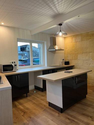 eine Küche mit einer Arbeitsplatte und einem Fenster in der Unterkunft Maison plein centre Sainte-Terre in Sainte-Terre