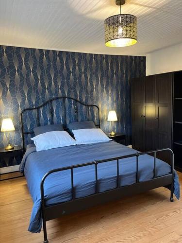 ein Schlafzimmer mit einem Bett mit blauer Bettwäsche und einer Wand in der Unterkunft Maison plein centre Sainte-Terre in Sainte-Terre