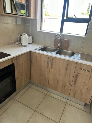 a kitchen with wooden cabinets and a sink and a window at Maadima, The Yard in Edenvale