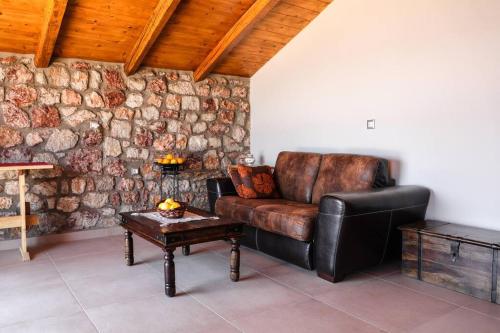 a leather couch in a room with a stone wall at Petronas Land House 2 in Archangelos