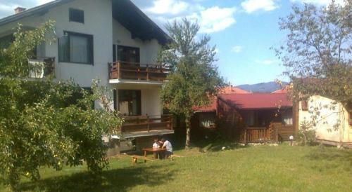 two people sitting at a table in front of a house at Guest House Raffe in Dobrinishte