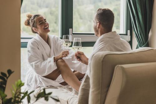 a man and a woman sitting in a room with glasses of wine at Seehotel Jägerwirt in Turracher Hohe