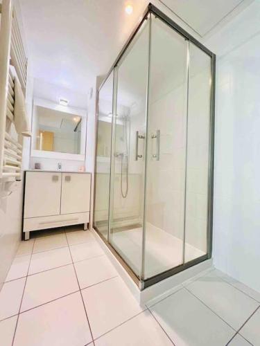 La salle de bains est pourvue d'une douche en verre et de carrelage. dans l'établissement Le White Pearl : Apt 4 Prs, Parking, Clim, à Antibes
