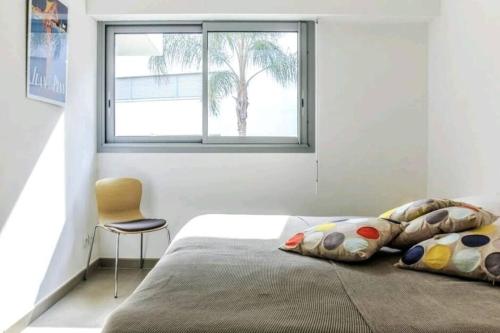 une chambre avec un lit avec une chaise et une fenêtre dans l'établissement Le White Pearl : Apt 4 Prs, Parking, Clim, à Antibes