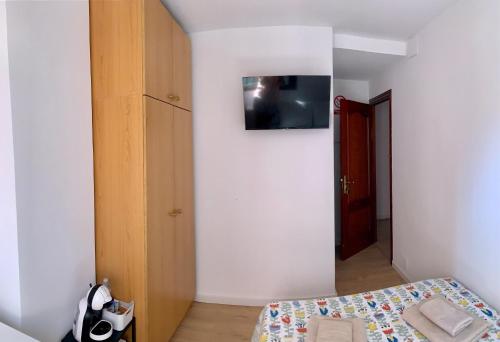 um quarto com uma cama e uma televisão na parede em Habitación González em Málaga