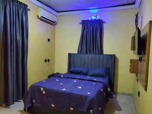 - une chambre avec un lit bleu et des rideaux bleus dans l'établissement TSOLID HOMES, à Ibadan