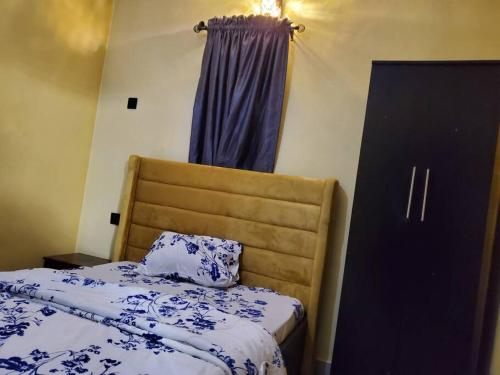 - une chambre avec un lit doté de draps bleus et blancs et une fenêtre dans l'établissement TSOLID HOMES, à Ibadan