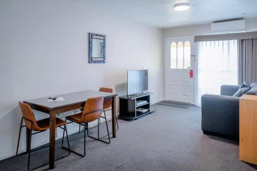 salon ze stołem, krzesłami i kanapą w obiekcie Merivale Court Motel & Apartments w mieście Christchurch