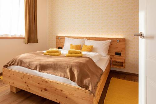 a bedroom with a wooden bed with two yellow pillows at Stadtfüchse plus Sauna in Bad Ischl