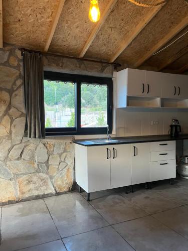 a kitchen with white cabinets and a stone wall at Olympos Ceratonia Dağ evi in Kumluca