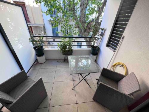 uma varanda com duas cadeiras e uma mesa e algumas plantas em Le Cosy Corner : Apt 2 pers de standing + Terrasse em Antibes