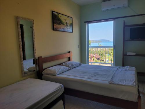 a bedroom with a bed and a mirror and a window at Solar do Forte Flats in Ubatuba