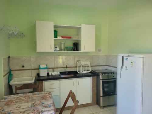 a kitchen with white cabinets and a white refrigerator at Solar do Forte Flats in Ubatuba