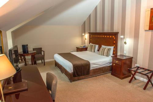 Schlafzimmer mit einem Bett, einem Tisch und Stühlen in der Unterkunft Manor Of Groves Hotel in Sawbridgeworth