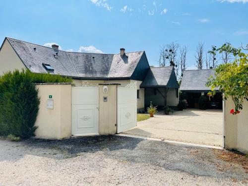 una casa con dos puertas de garaje y un camino de entrada en The Paillottes of Haute Mazère with swimming pool en Pocé-sur-Cisse