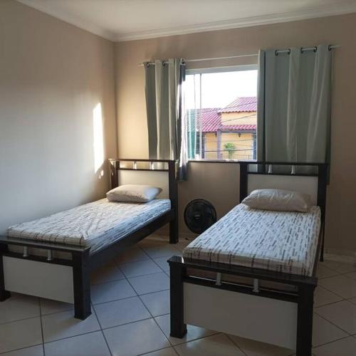 two beds sitting in a room with a window at Casa Jardim Belvedere VR in Volta Redonda