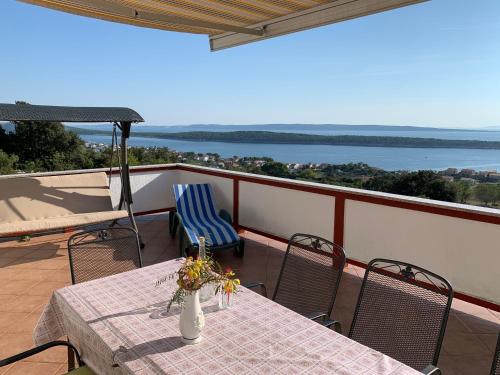 a table and chairs on a balcony with a view of the ocean at Apartments Jaca in Rab