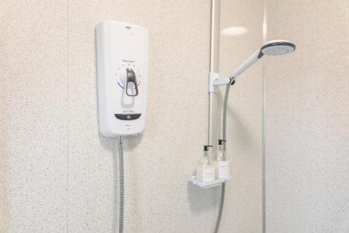 a white soap dispenser on the wall of a shower at ZSKstays! Comfortable home, nice area, free parking and large garden! in Hull