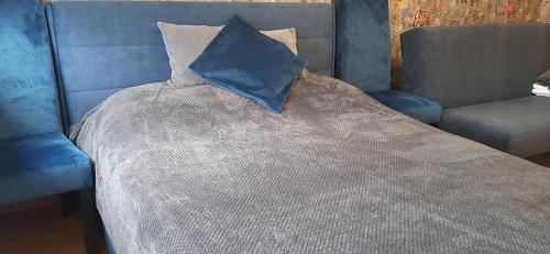 a bed with a blue comforter with a pillow on it at Mieszkanie w Giżycku in Giżycko